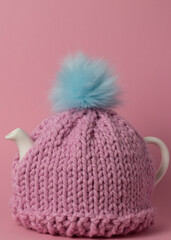 a teapot with a pink knitted tea cozy