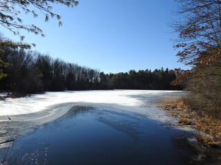 The beautiful winter scenery of a partially frozen Lake Wintergreen, in West Rock Ridge State Park, Hamden, Connecticut.