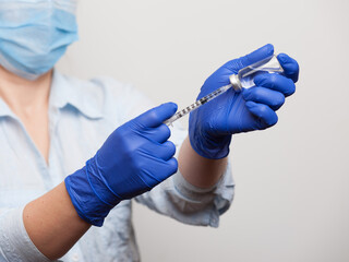 hands of a nurse in medical gloves dialing a vaccine or medicine for injection into the syringe