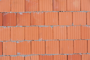 Laying red ceramic blocks at a construction site. Warm ceramics: features and specifications. The texture of red blocks wall for wallpaper or background
