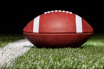 Low angle view of a football on a grass field with black background