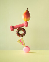 Creative balanced lifestyle concept. Minimalistic composition with sweets, fruit and workout on pastel yellow background. Eating healthy food idea.