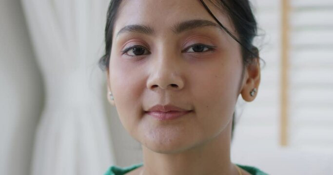 Young asia teen girl college influencer vlogger look at camera happy cozy day enjoy relax time calm indoor life. Front view close-up latin lady model face gen Z people good skin health care at home.