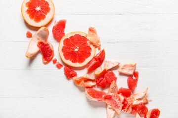 Tasty grapefruit pieces on light wooden background