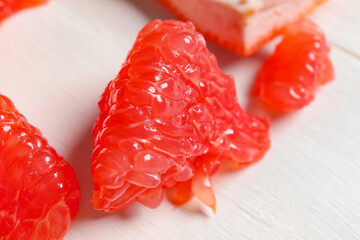 Tasty grapefruit pieces on light wooden background, closeup