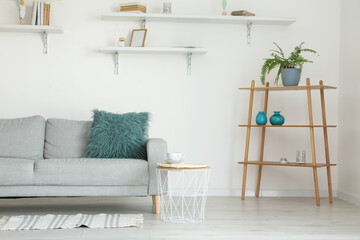 Stylish grey sofa with rack in modern interior of living room