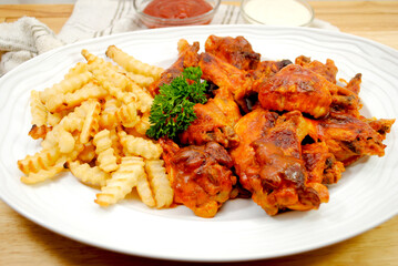 A Platter of Spicy baked Buffalo Wings Served with French Fries