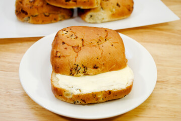 A Buttered Onion Roll Served on a White Plate	
