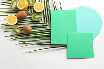Composition with blank cards, palm leaf and fruits on white background