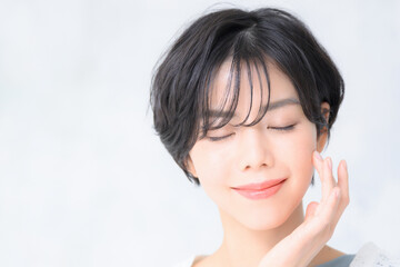 美容などに使いやすい目を閉じ顔に手を添える美しい日本人女性　コピースペース