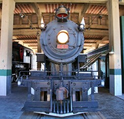 Vintage steam locomotive with the head lamp burning sitting on the rails at the station.  