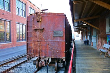 Vintage rusty rail car sitting on a track in front of a station.  