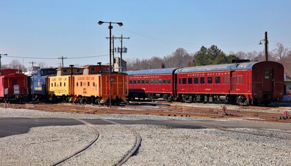 Vintage Pullman rail cars and caboose sitting on a track at a museum.  