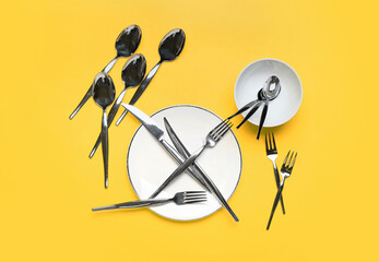 Plates and set of cutlery on color background