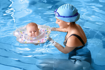 Young mother and her adorable baby with inflatable ring in swimming pool