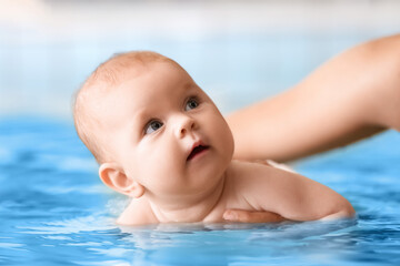 Adorable little baby with coach in swimming pool, closeup