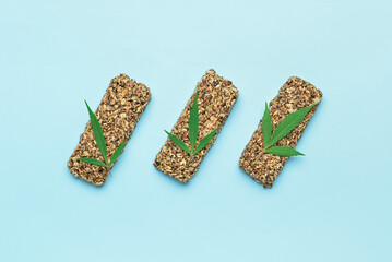 Protein bars with hemp seeds and leaves on blue background