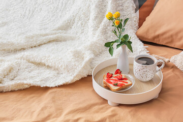 Obraz na płótnie Canvas Tray with tasty breakfast and vase with flowers on comfortable bed