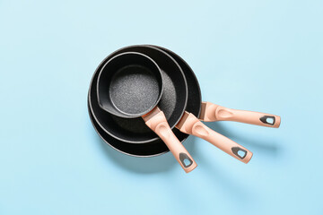 Frying pans and saucepan on color background - obrazy, fototapety, plakaty