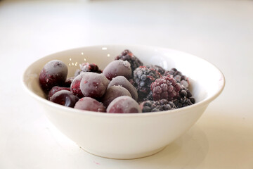 On a white background, in a white cup, delicious berries are defrosted