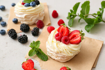 Tasty Pavlova cakes with fresh berries on light background