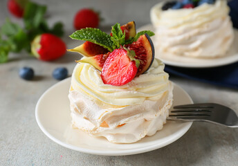 Plate of tasty Pavlova cake with berries on grunge background