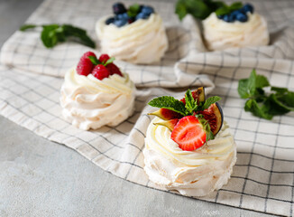 Tasty Pavlova cakes with fresh berries on grunge background