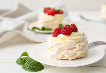 Plate of tasty Pavlova cake with fresh berries on light wooden background