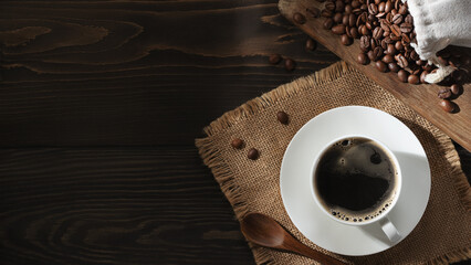 White cup of fresh hot coffee and coffee beans on the table, top view, flatl ay, copyspace
