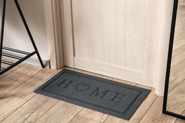 Modern mat near light wooden door in hall