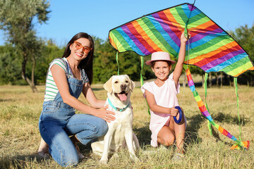 Little girl with kite, her mother and cute dog in park