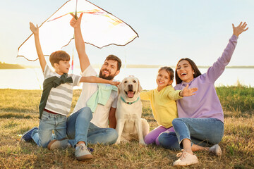 Happy family with cute dog and kite outdoors