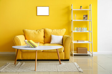 Interior of bright living room with yellow sofa, coffee table and shelving unit