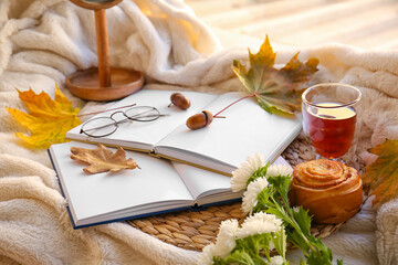 Fototapeta na wymiar Books, eyeglasses, cup of tea and autumn decor on plaid