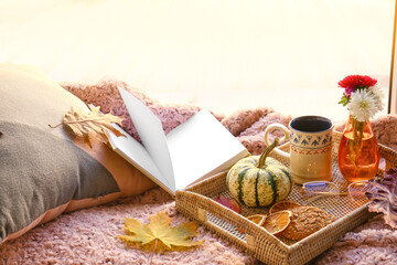 Book, cup of coffee, cookies and autumn decor on windowsill