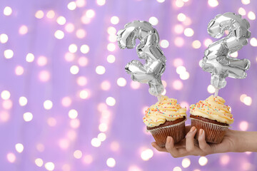 Woman holding Birthday cupcakes against blurred background