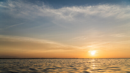 Sunset sky over sea in the evening with orange sunlight