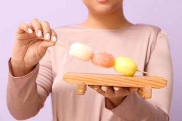 Beautiful Asian woman with tasty Japanese mochi on color background, closeup