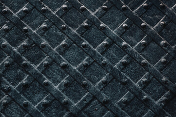 Old black metal door with a diamond pattern close-up. Vintage background closeup. Medieval forging technologies.