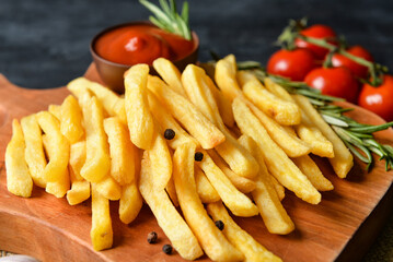 Wooden board with tasty french fries on table, closeup