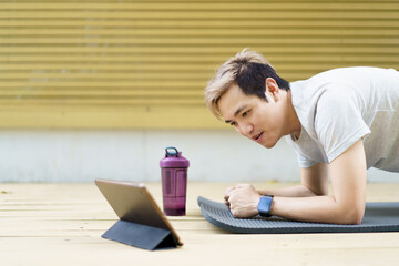 Active sportsman doing a plank exercise and making a video call with a friend and online sport training coach.