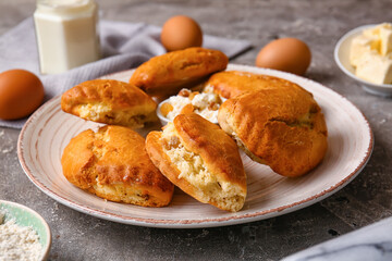 Plate of tasty sochniki with cottage cheese on grey background