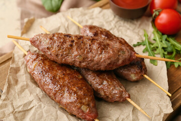 Wooden board of skewers with tasty lula kebab on table, closeup