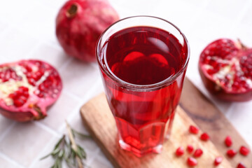 Glass of delicious pomegranate juice on tile background