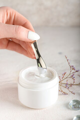 Female hand with natural cosmetic cream on light background, closeup
