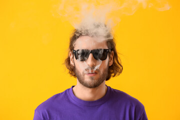 Fototapeta premium Smoking young man on yellow background