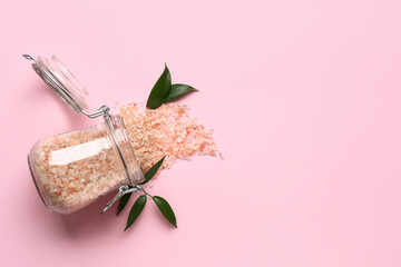 Glass jar of sea salt on pink background