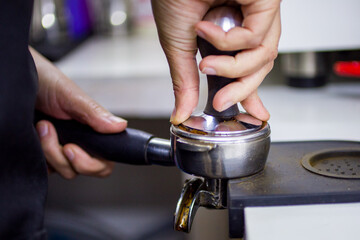 tempering coffee by hand in a coffee shop