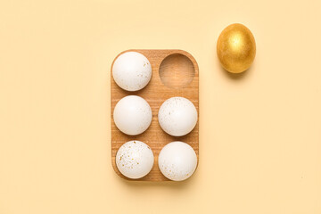 Wooden holder with beautiful Easter eggs on color background