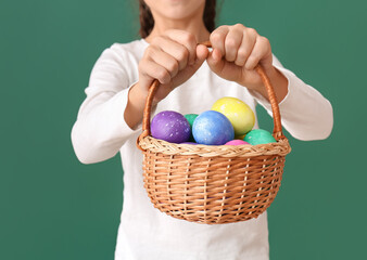 Funny little girl with Easter basket on green background, closeup